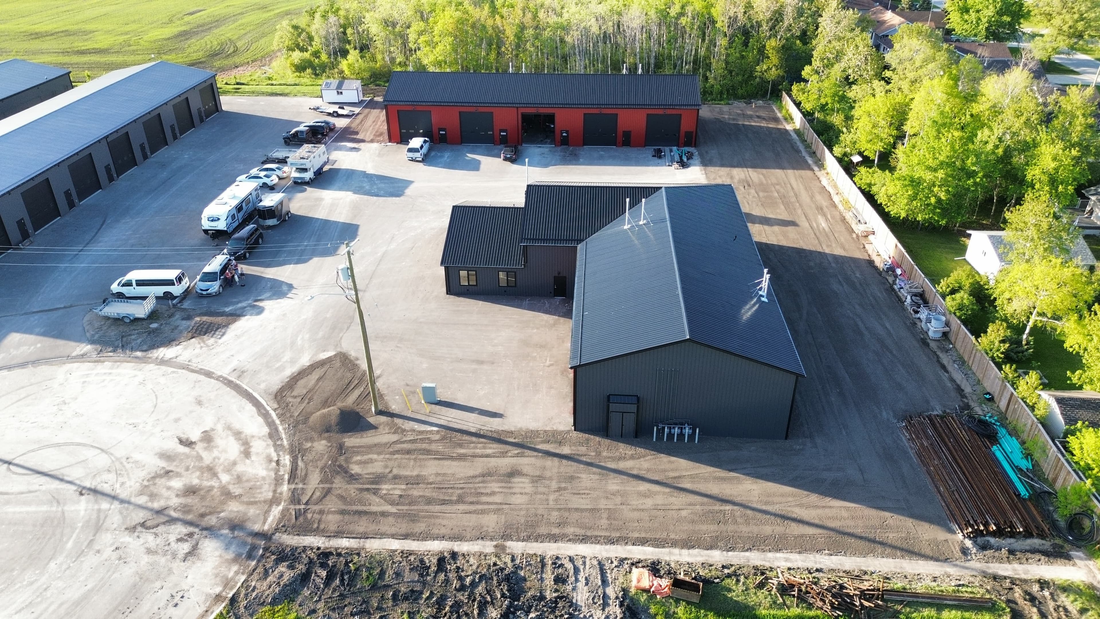 Aerial view of a commercial complex with red and grey buildings and a dirt lot.